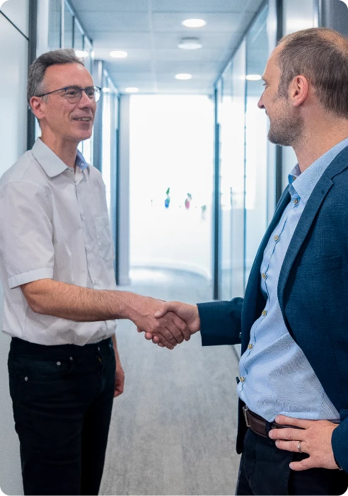 Une collaboratrice du cabinet comptable accueillant un client avec une poignée de main, symbole de confiance et d’accompagnement personnalisé.