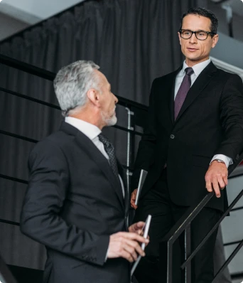 deux hommes en costard en train de discuter dans un escalier