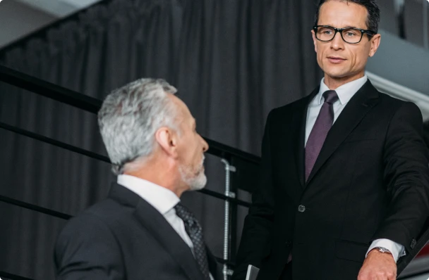 deux hommes en costard en train de discuter dans un escalier